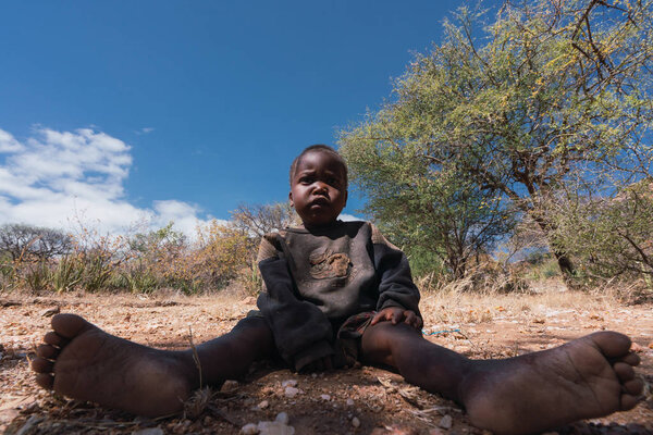 Eyasi lake, Tanzania, november, 23, 2019: African child sitting on the floor in the savannah Royalty Free Stock Images