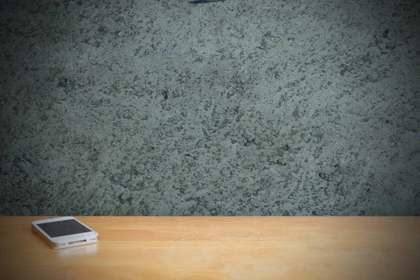 Çimento duvar önünde ahşap masa üstünde Smartphone