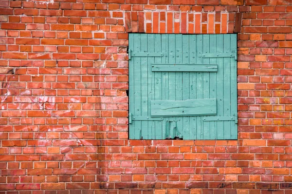 Red brick wall with a green wooden window — Stock Photo, Image