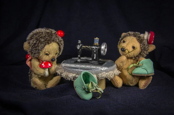 Two dolls of shoe-hedgehogs while working at the table with a sewing machine