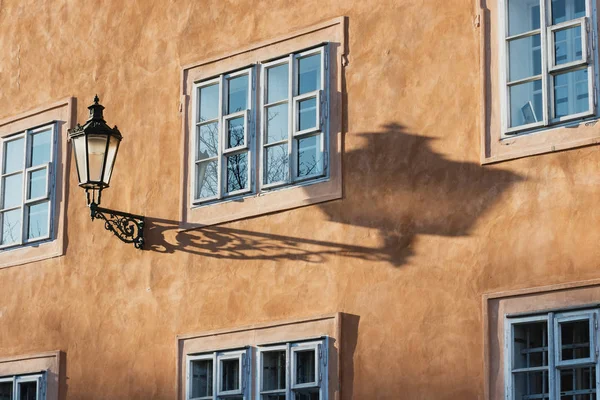 Una vieja lámpara de calle y sombra en una pared con una ventana — Foto de Stock