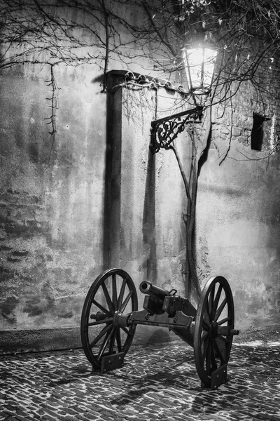 L'angolo buio castello storico con cannone acceso da lampada storica in BW — Foto Stock