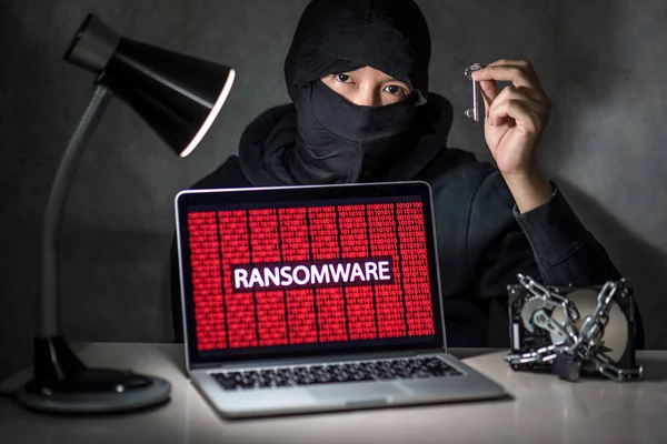 Hacker with computer screen showing ransomware attacking — Stock Photo, Image