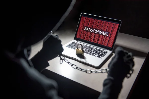 Mand hacker låsning computer ved hjælp af kæde og hængelås - Stock-foto