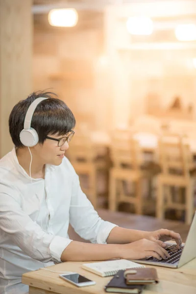 Asiático jovem com fones de ouvido ouvindo música — Fotografia de Stock