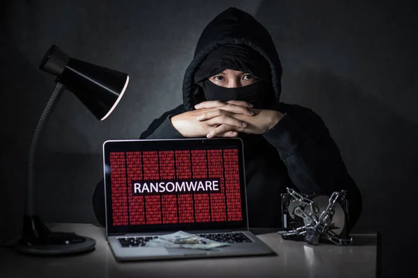 Hacker with computer screen showing ransomware attacking — Stock Photo, Image