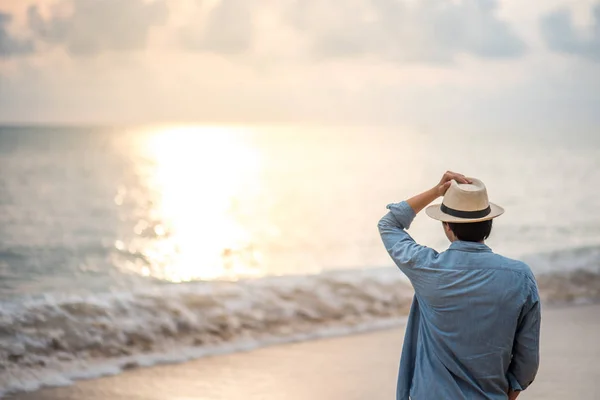 Young man standing on the beach and see beautiful sunset — Stock Photo, Image