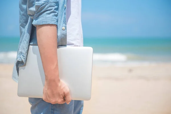 Un bărbat care ține laptopul pe plajă — Fotografie, imagine de stoc