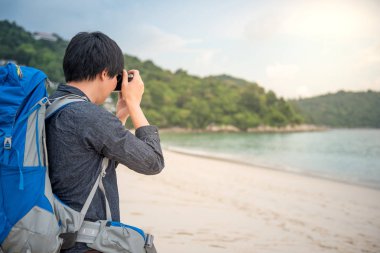 Genç Asyalı backpacker sahilde fotoğraf çekmek