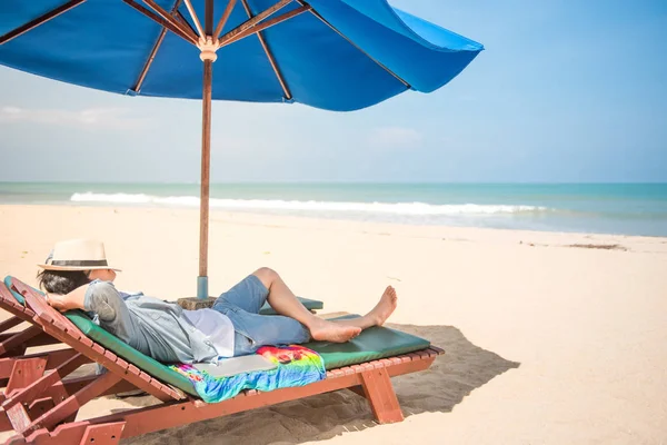 Молодой Асаин лежит на скамейке на пляже — стоковое фото