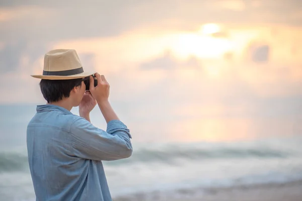 A fiatalember utas fotózni naplementét, trópusi tengerparton — Stock Fotó