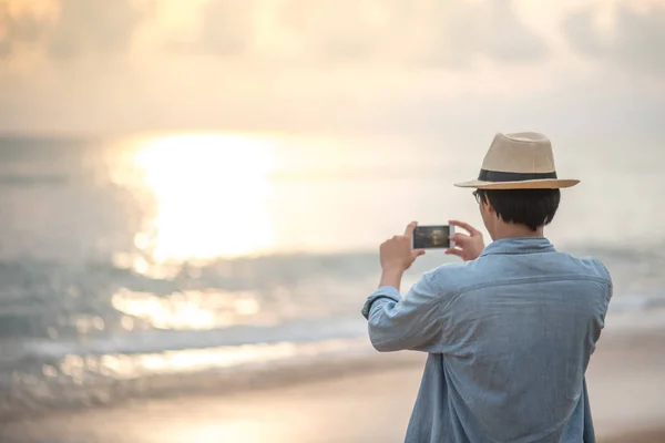 A fiatalember fotózni a parton smartphone — Stock Fotó