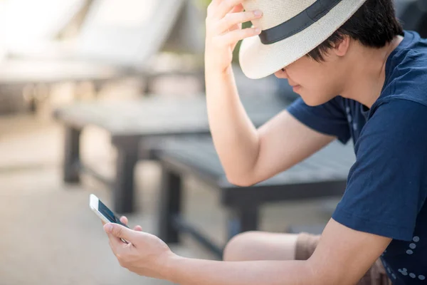 Ung asiatisk mann som bruker smarttelefon i feriefot – stockfoto