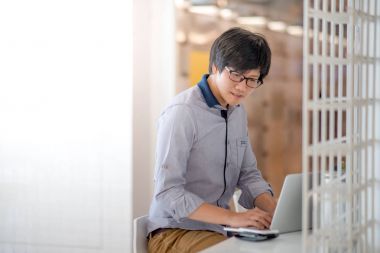 Genç Asyalı adam kafede dizüstü bilgisayar ile çalışma