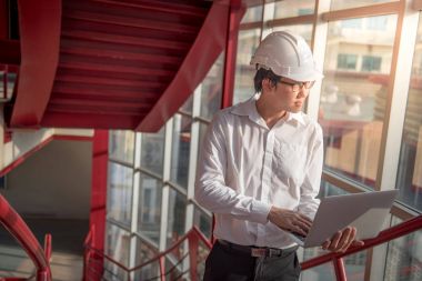 Genç Asyalı mühendis veya mimar laptop ile çalışma