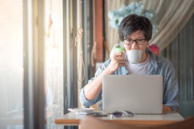 Kahve süre içinde dizüstü bilgisayar kullanan genç Asyalı adam