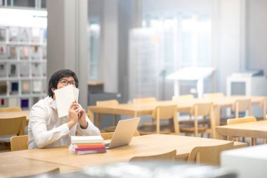 Genç Asyalı Üniversite öğrenci okuma kitabı Kitaplığı'nda