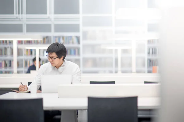 Jovem estudante universitário asiático trabalhando na biblioteca — Fotografia de Stock