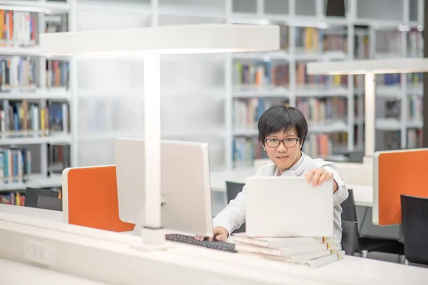 Jeune étudiant asiatique travaillant dans une bibliothèque — Photo