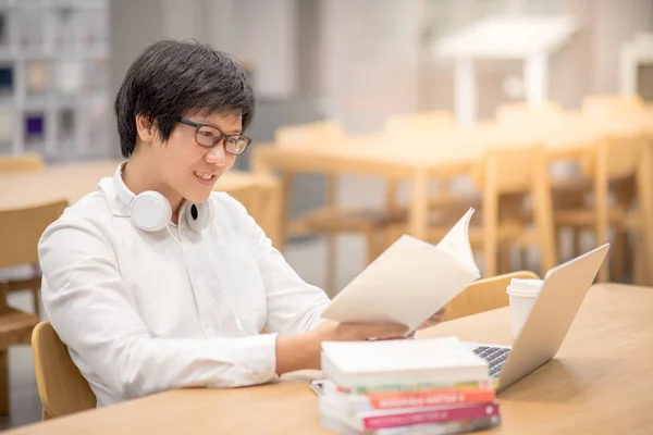 Joven estudiante universitaria asiática leyendo libro en biblioteca — Foto de Stock