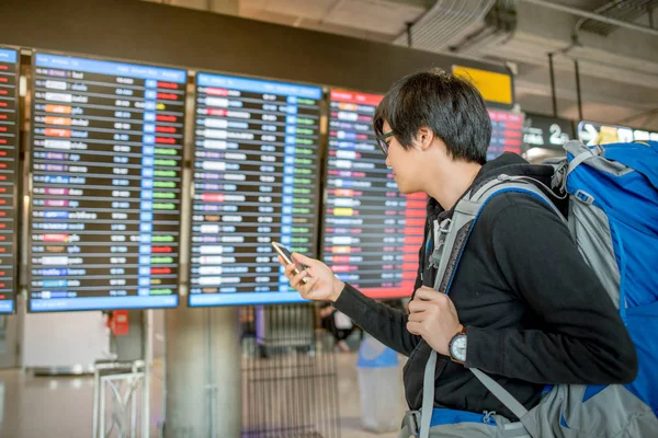 Young asian man with backpack bag checking for his flight — Stock Photo, Image