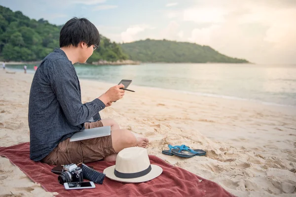 Fiatal ázsiai férfi tabletta a strandon — Stock Fotó