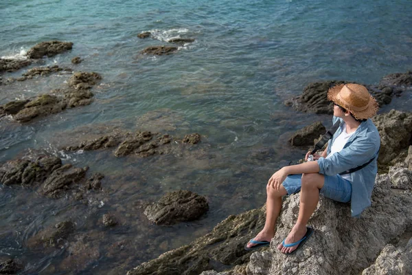 Young asian man traveler sitting on the rock cliff — Stock Photo, Image