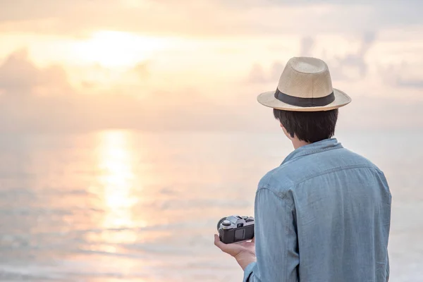 Młody człowiek podróżnik, patrząc na zachód słońca na tropikalnej plaży — Zdjęcie stockowe