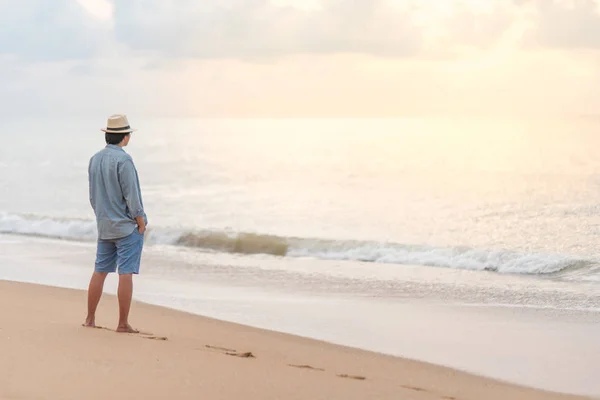 समुद्र तट पर युवा एशियाई आदमी सूर्यास्त देख रहा है — स्टॉक फ़ोटो, इमेज
