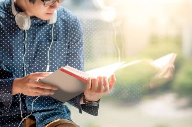 Genç Asyalı adam kitaplığındaki kitap okumak