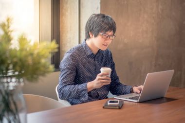 Genç Asyalı adam ofiste dizüstü bilgisayar ile çalışma