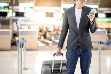 Genç Asyalı adam akıllı telefon Havaalanı terminal kullanarak