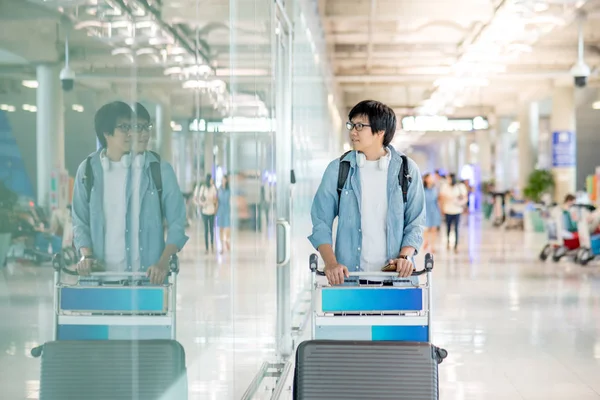 Joven asiático hombre caminando con aeropuerto carro — Foto de Stock