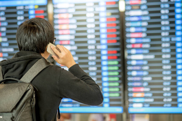 Young asian man with backpack bag checking his flight