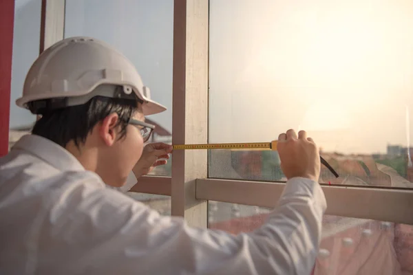 Mladý inženýr muž páskou opatření na rám okna — Stock fotografie