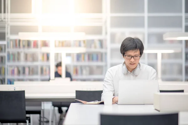 Jeune homme asiatique étudiant universitaire travaillant dans une bibliothèque — Photo