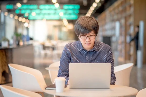  Genç Asyalı adam kafede dizüstü bilgisayar ile çalışma