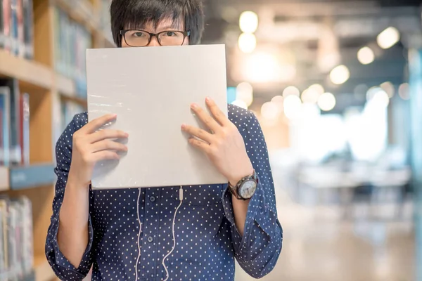 Young Asian man student lifting white book in library