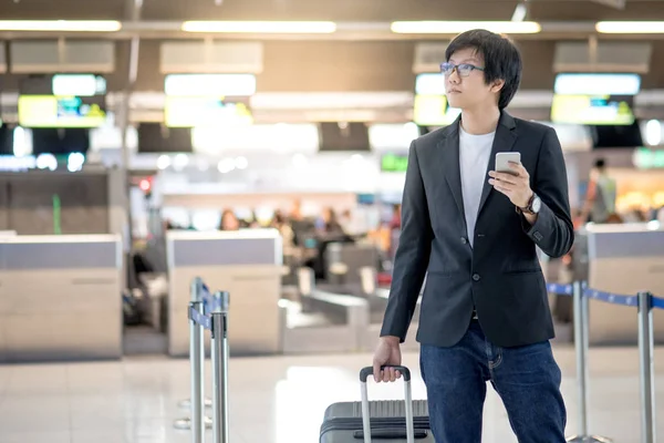 Young asian man using smartphone in airport terminal