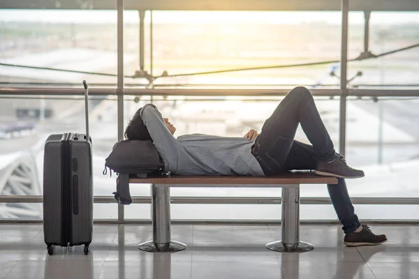 Ασιατικές νεαρός ξαπλωμένος σε πάγκο στο τερματικό σταθμό του αεροδρομίου — Φωτογραφία Αρχείου