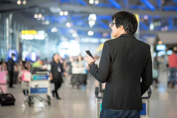 Joven asiático hombre usando smartphone en aeropuerto terminal — Foto de Stock