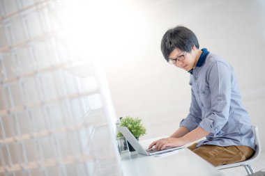 Genç Asyalı adam kafede dizüstü bilgisayar ile çalışma