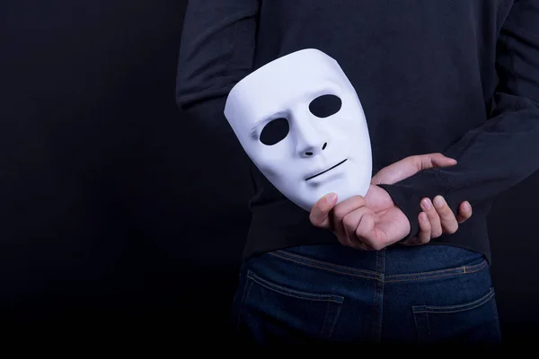 Ο άνθρωπος μυστήριο κρατώντας λευκή μάσκα στο πίσω μέρος — Φωτογραφία Αρχείου