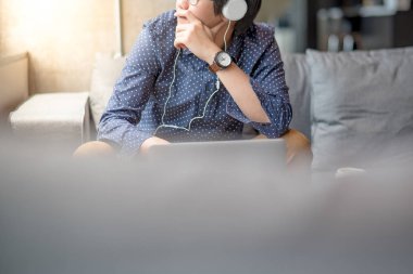 dizüstü bilgisayar ile kanepede oturan genç Asyalı adam