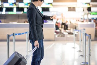 Havaalanında uçuş için bekleyen genç Asyalı adam