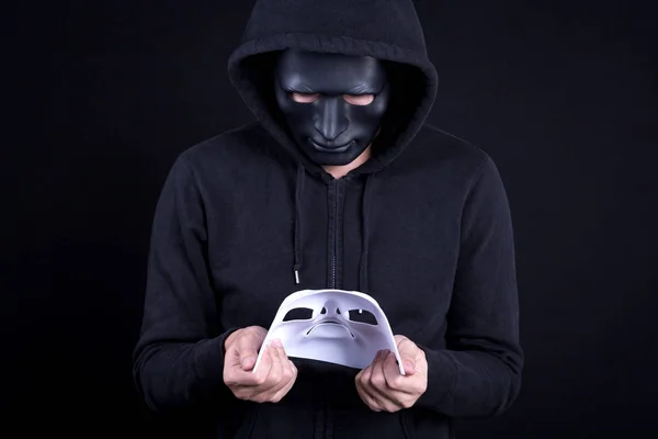 Mystery man holding and looking at white mask — Stock Photo, Image