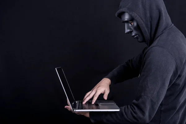 Pria hacker dengan topeng hitam membawa laptop — Stok Foto