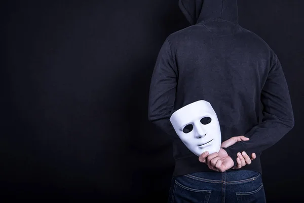 Tajemnica człowieka trzyma białą maskę w plecy — Zdjęcie stockowe