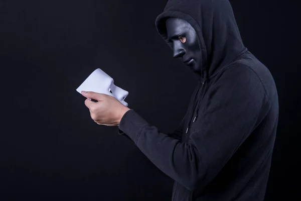 Hombre misterioso sosteniendo y mirando la máscara blanca — Foto de Stock