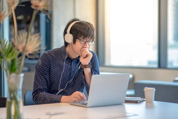 Çalışma alanı içinde laptop ile çalışan genç Asyalı adam